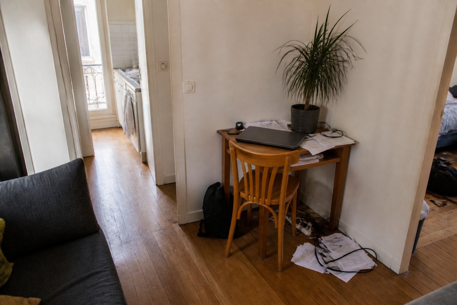 Petit bureau improvisé dans un coin de salon avec câbles et papiers.