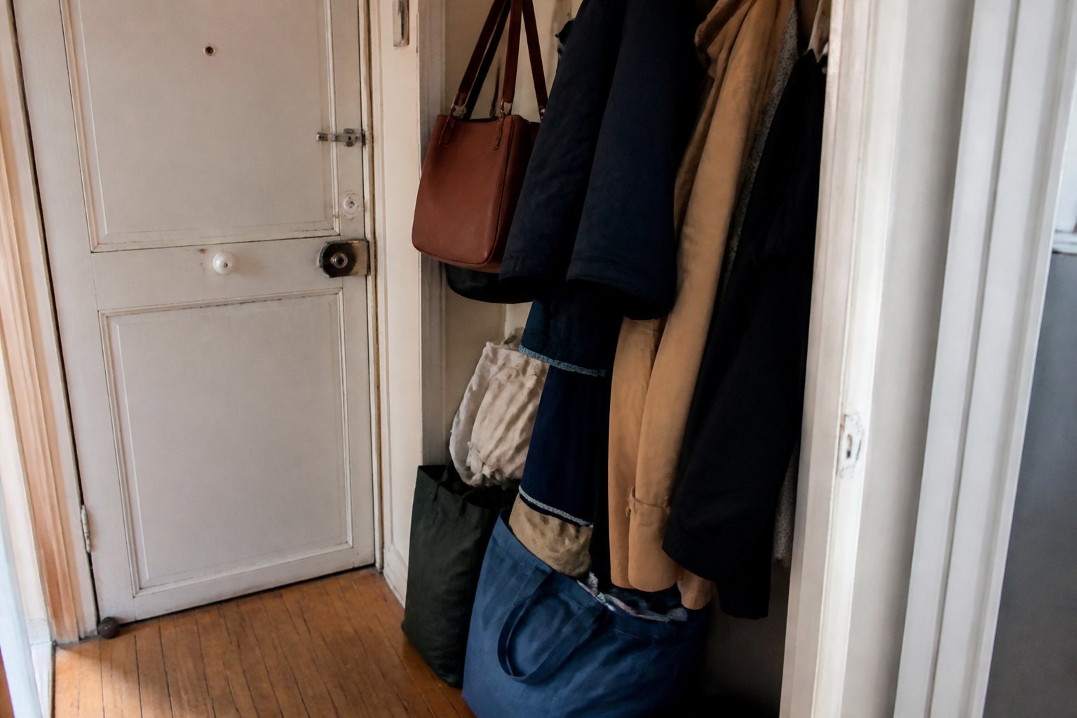 Zone étroite près d’une porte encombrée de manteaux et de sacs.