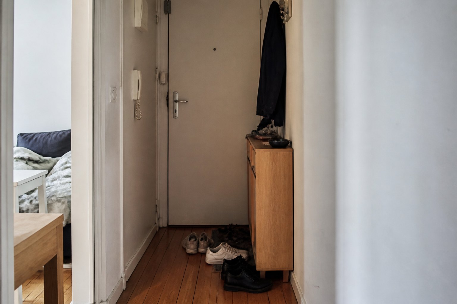 Entrée étroite encombrée par plusieurs paires de chaussures.
